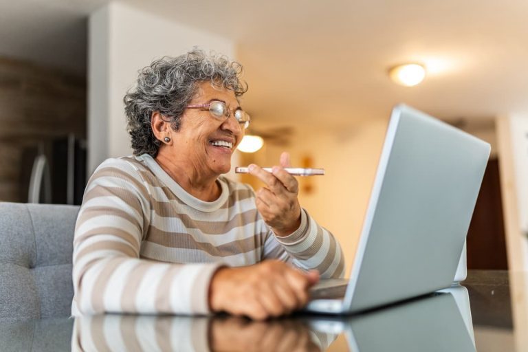 Senior talking on phone and looking at laptop screen