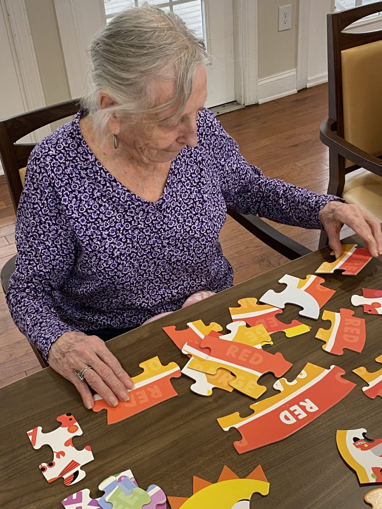 Elderly resident sitting at table completing puzzle