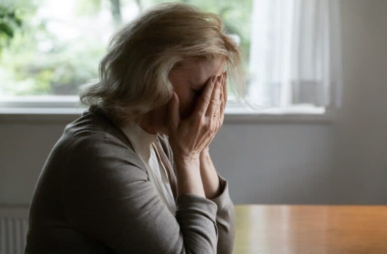 senior woman covering face with hands