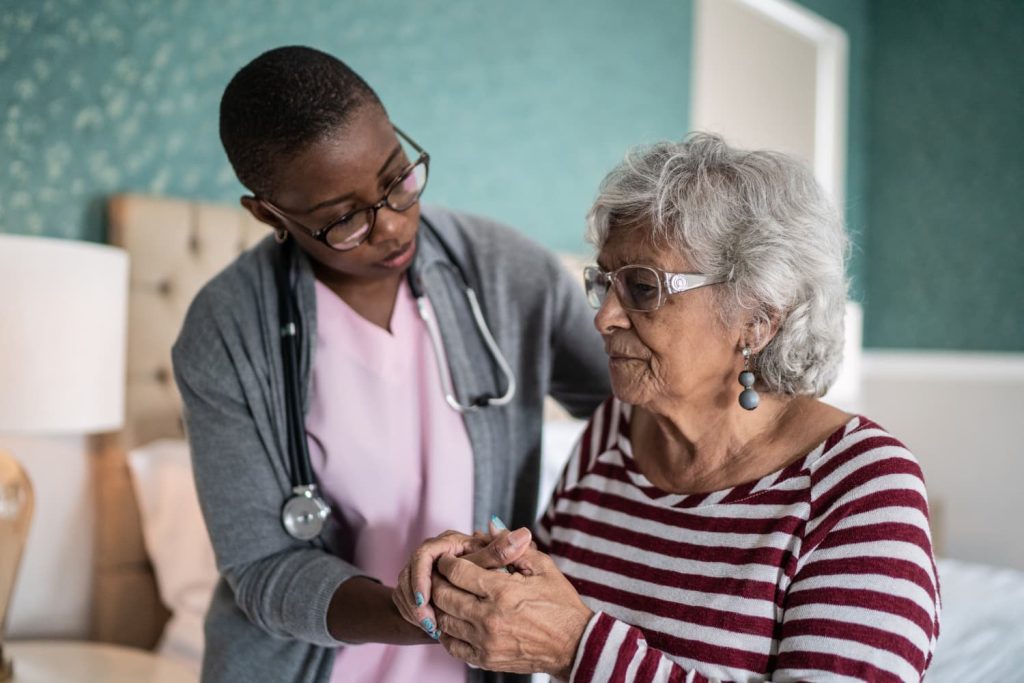 Staff member of memory care community helping elderly woman with Alzheimer's disease