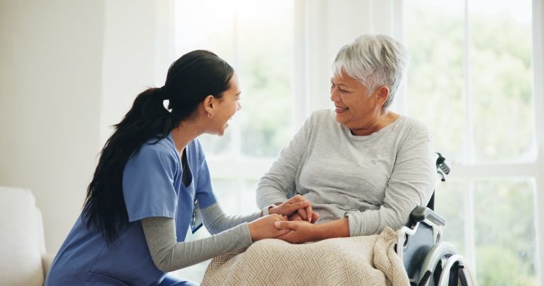 Memory care community staff member talking to senior in wheelchair