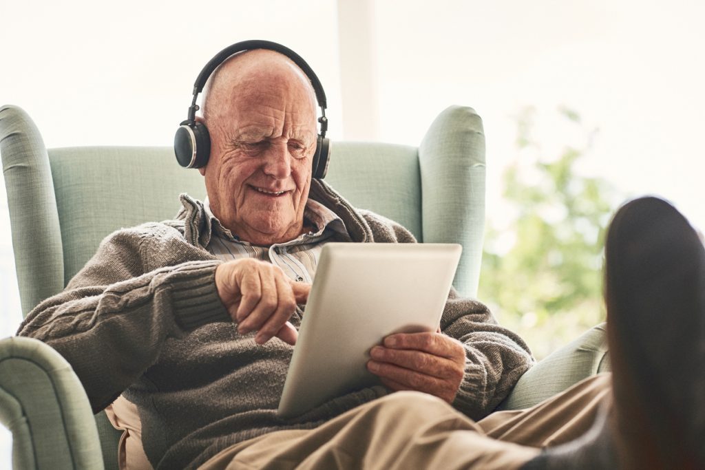Resident sitting in chair and using tablet to stimulate mind and engage cognitive function